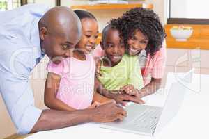 Cute siblings using laptop together with parents