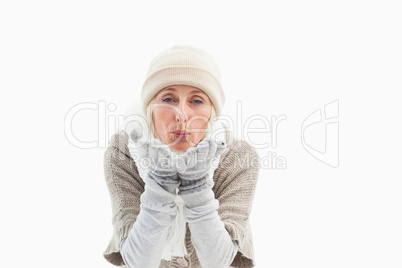 Mature woman in winter clothes blowing kiss