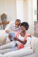 Happy couple relaxing together on the couch using tablet