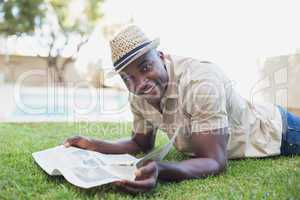 Smiling man relaxing in his garden reading newspaper