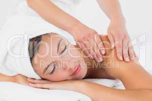 Attractive young woman receiving shoulder massage at spa center