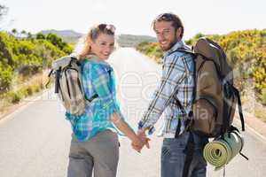 Attractive couple standing on the road holding hands smiling at