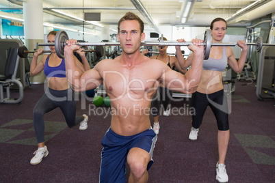 Fitness class lifting barbells together