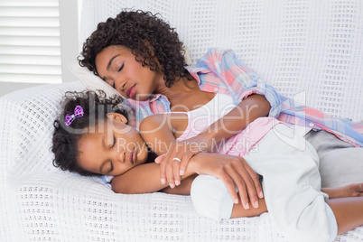 Cute daughter sleeping with mother on the sofa