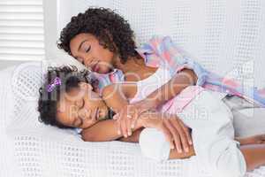 Cute daughter sleeping with mother on the sofa
