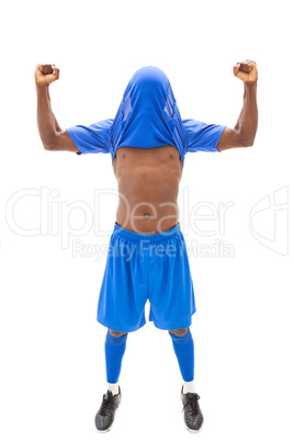 Excited football player in blue cheering with jersey over head