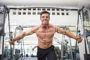 Shirtless muscular man using resistance band in gym