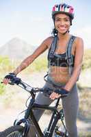 Fit woman going for bike ride smiling at camera