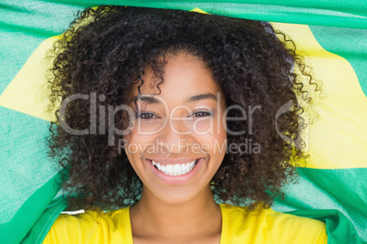 Pretty girl in yellow tshirt holding brazilian flag smiling at c