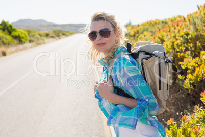 Attractive blonde hitch hiking on rural road