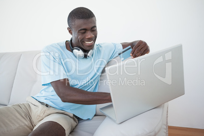 Casual man sitting on sofa using laptop to shop online