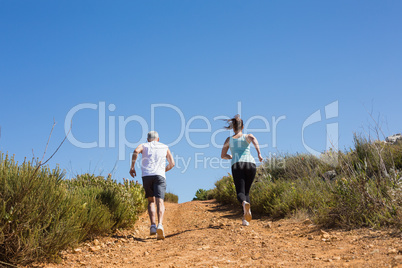 Fit couple jogging up mountain trail