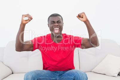 Cheering football fan in red sitting on couch