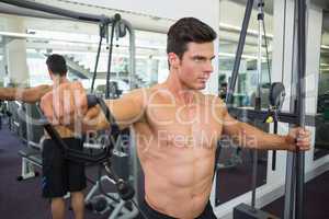 Shirtless muscular man using resistance band in gym