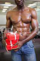 Mid section of a muscular man with gift boxes