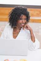 Pretty woman in bathrobe using laptop at table