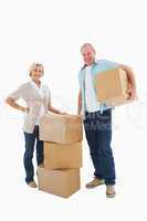 Older couple smiling at camera with moving boxes