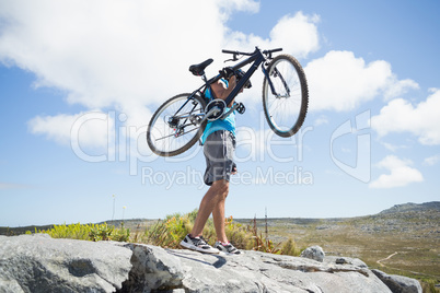 Fit man walking on rocky terrain holding mountain bike