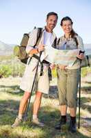 Hiking couple consulting the map in the countryside