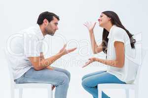 Couple sitting on chairs arguing