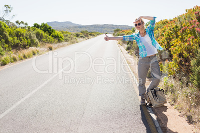 Attractive blonde hitch hiking on rural road