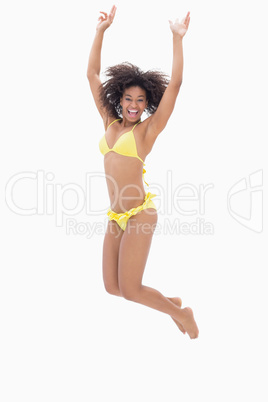 Athletic girl in yellow bikini jumping and smiling at camera