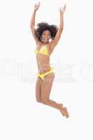 Athletic girl in yellow bikini jumping and smiling at camera