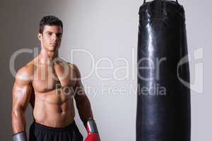 Portrait of a shirtless muscular boxer with punching bag