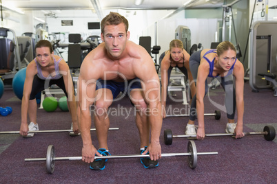 Fitness class lifting barbells together