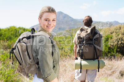 Attractive hiking couple walking on mountain trail woman smiling