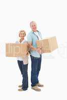 Older couple smiling at camera holding moving boxes