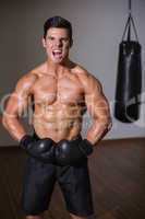 Shirtless muscular boxer shouting in health club