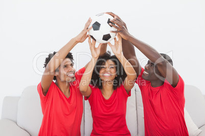 Football fans sitting on couch holding ball