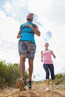 Fit attractive couple jogging down mountain trail