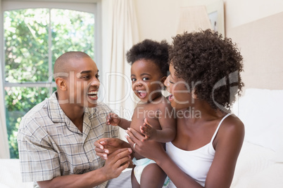 Happy couple on bed with baby daughter