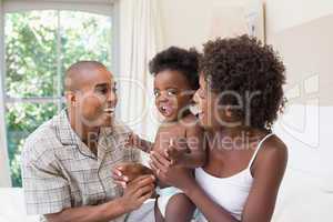 Happy couple on bed with baby daughter