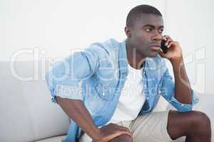 Casual man sitting on sofa on the phone