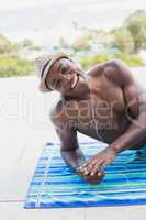 Handsome shirtless man listening to music poolside