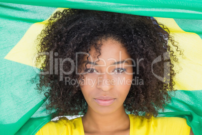 Pretty girl in yellow tshirt holding brazilian flag looking at c