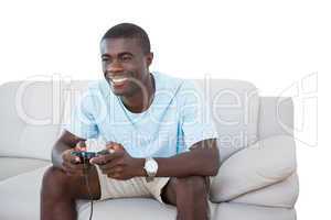 Smiling man sitting on couch playing video games