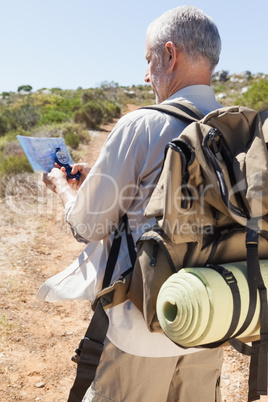 Handsome hiker consulting the map in the countryside
