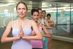Yoga class in tree pose in fitness studio