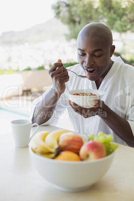 Handsome man in bathrobe having breakfast outside