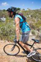 Fit man cycling up mountain trail