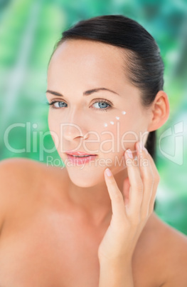 Beautiful nude brunette applying face cream