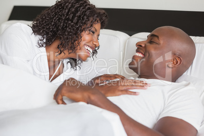 Happy couple laughing together in bed