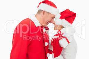 Festive older couple smiling at each other and holding gift