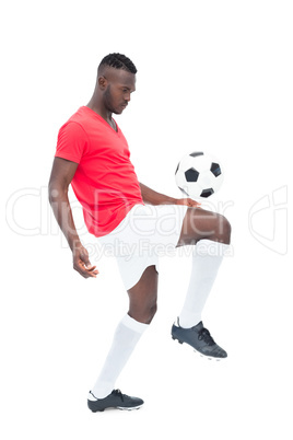 Football player in red jersey controlling ball