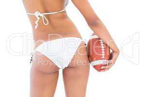 Fit girl in white bikini holding american football