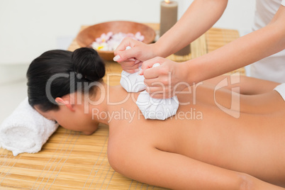 Beautiful brunette enjoying a herbal compress massage